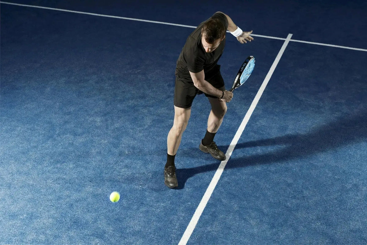 Joueur de padel frappant une balle en puissance sur un terrain bleu