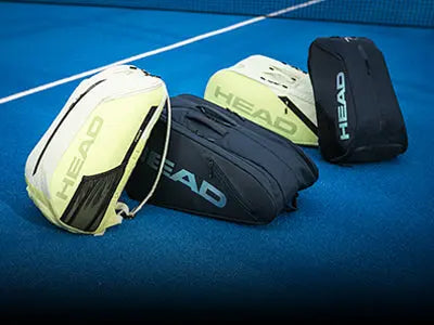 Trois sacs de padel Head jaunes et noirs posés sur un terrain bleu, collection de sacs et housses de padel