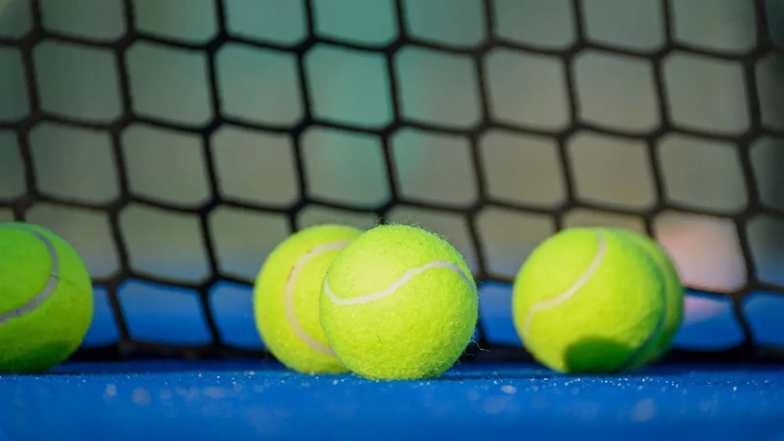 Deux étuis de balles de Padel, de la marque Head, disposés sur un terrain de Padel.